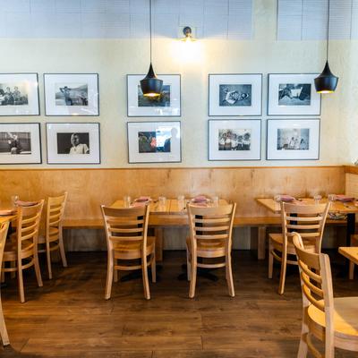 Dining area with wooden tables and framed photographs on the wall.