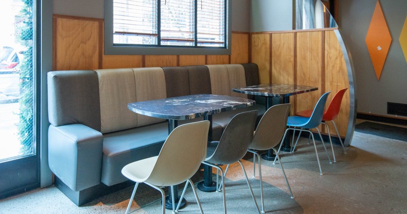 Modern cafe interior with booth seating, marble tables, and colorful chairs