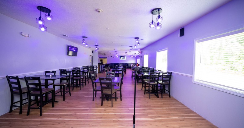 Interior, dining area, tables for four, purple neon lighting, windows with blinds on the right