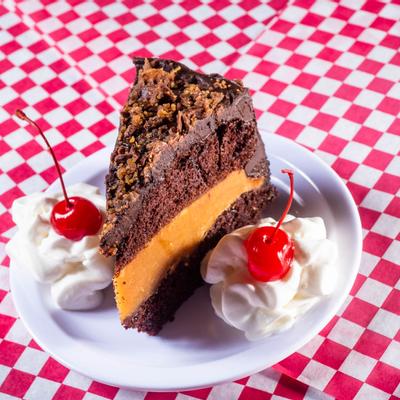 Chocolate peanut butter cake served with cherries and cream as decorations