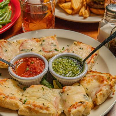 Bruschetta topped with pepperoni and cheese, served with pesto and marinara sauces.