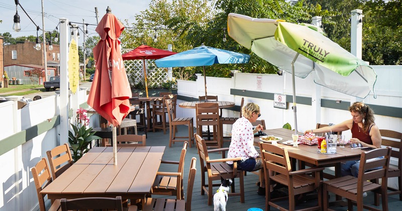 Outdoor seating, tables and chairs with parasols, two guests dining