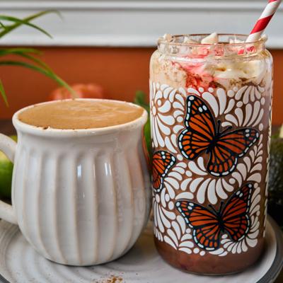 Mexican hot chocolate beside a chocolate dessert drink served in a butterfly glass.
