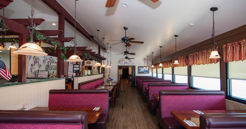 Interior of a restaurant with red booth seating, hanging pendant lights, and ceiling fans