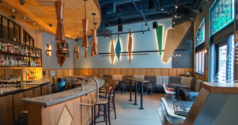 Stylish bar interior with a stocked bar, pendant lights, and geometric wall art