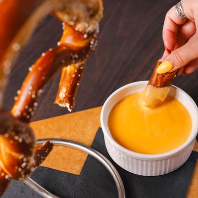 A hand dipping a piece of a pretzel.