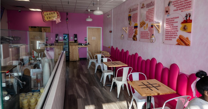 Interior of a dessert shop - pink decor, wooden and metal seating, informational wall signs