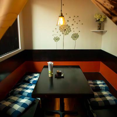 Cozy restaurant corner booth with patterned cushions and floral wall art.
