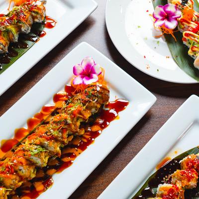 Sushi assortment served on rectangular and round plates.
