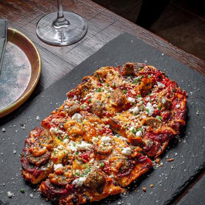Chicken Meatball flatbread with tomato sauce, green chili sauce, Asiago, and goat cheese.