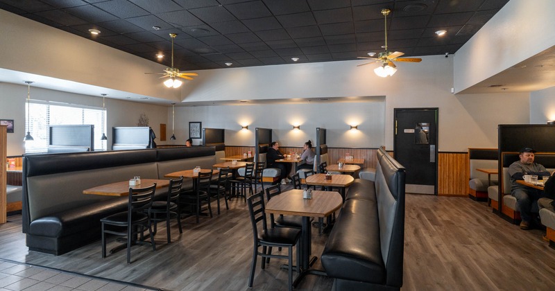Spacious diner with black and wooden decor, featuring booths and tables