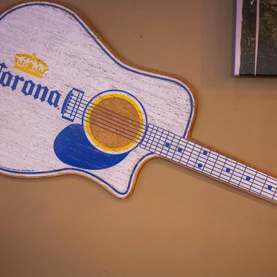 Guitar-shaped sign with a  beer logo on a wall.