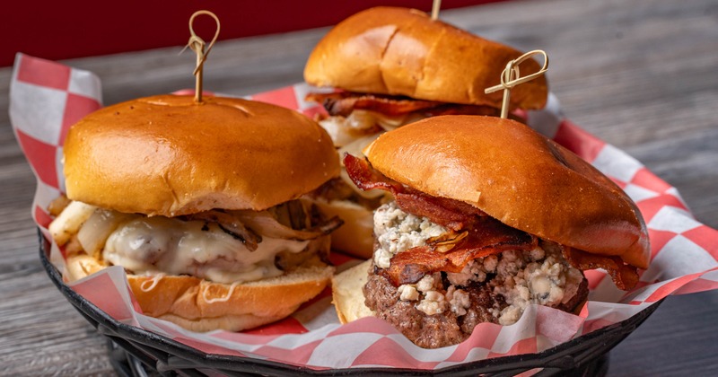 Three burgers with varioius toppings, served in a basket