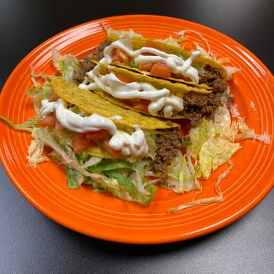 Tacos with lettuce, diced tomatoes, and sour cream.