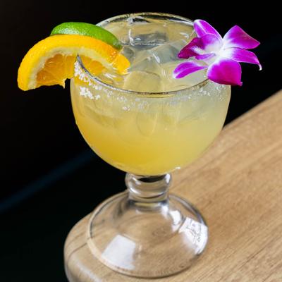Margarita served in salt-rimmed glass, garnished with citrus slices and a flower.