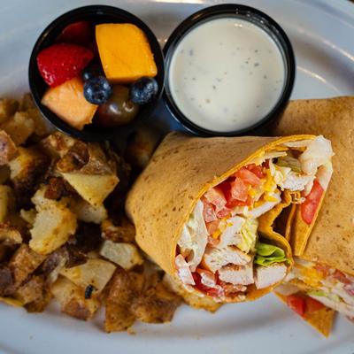 Chicken and bacon wrap served with a cup of fresh fruit and ranch.