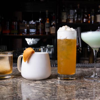A lineup of four distinct cocktails served on a bar top.