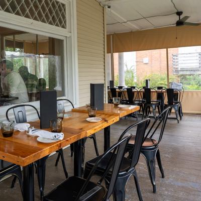 Outdoor patio dining area featuring rustic wooden tables and black metal chairs.