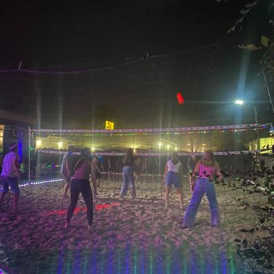 People playing beach volleyball at night under lights.