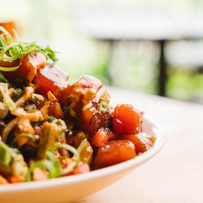 Poke nachos topped with sauce and herbs, close view.