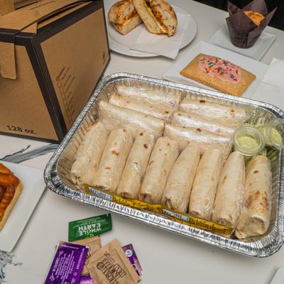 Tray of wrapped burritos with sauces.