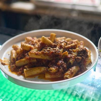 A dish of rigatoni pasta covered in a hearty meat-based bolognese sauce.