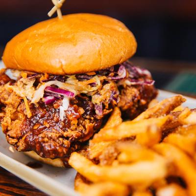 Fried Chicken Sandwich, with BBQ sauce, cabbage, peanut dressing, cucumber, jalapenos, and fries.