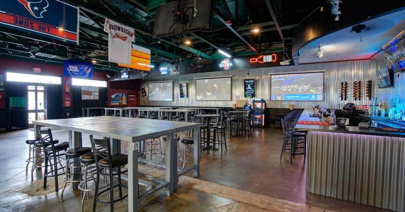 Interior, wide view, high tables and chairs ready for guests, bar on the right