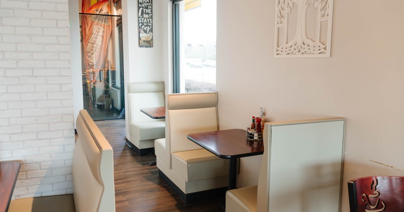 Restaurant interior with beige booths, dark wooden tables