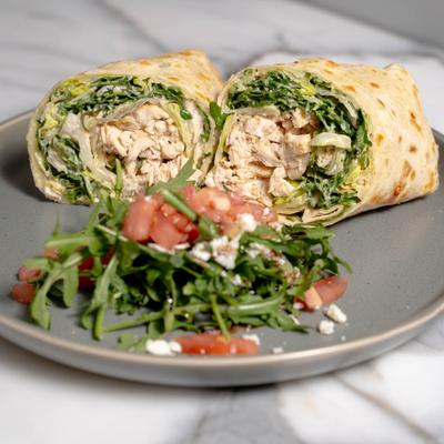 Grilled Chicken Caesar Wrap served with arugula and tomato salad on the side.
