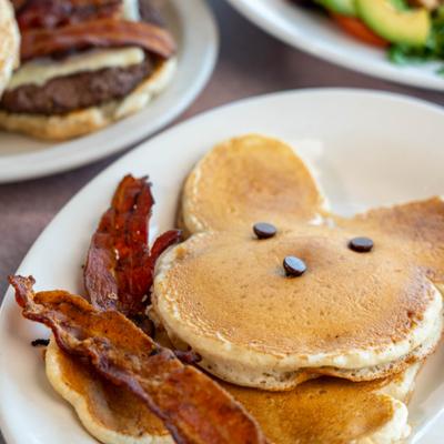 Plate of pancakes served alongside strips of bacon.