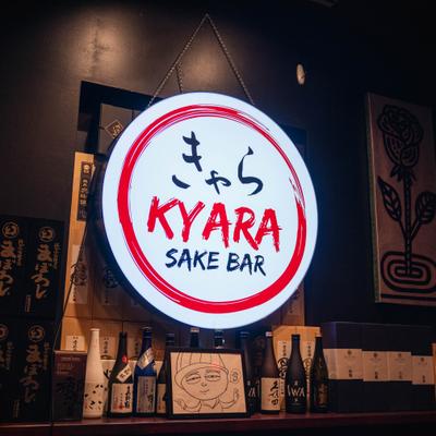 Restaurant's indoor signage with the counter stocked with various bottles of sake.