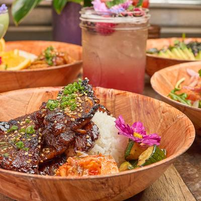 Marinated Korean beef bowl with a berry lemonade and other dishes in the background.