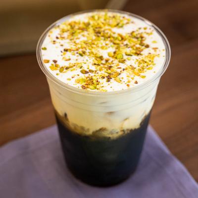 Pistachio cold brew served in a clear plastic cup.