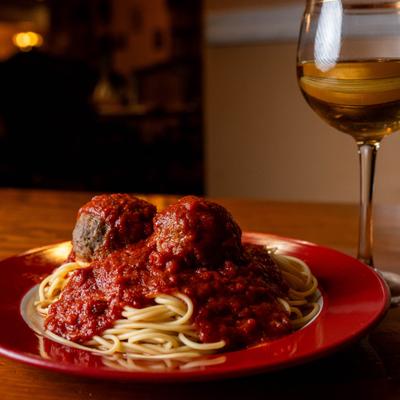 Spaghetti and meatballs in tomato sauce, served with white wine.
