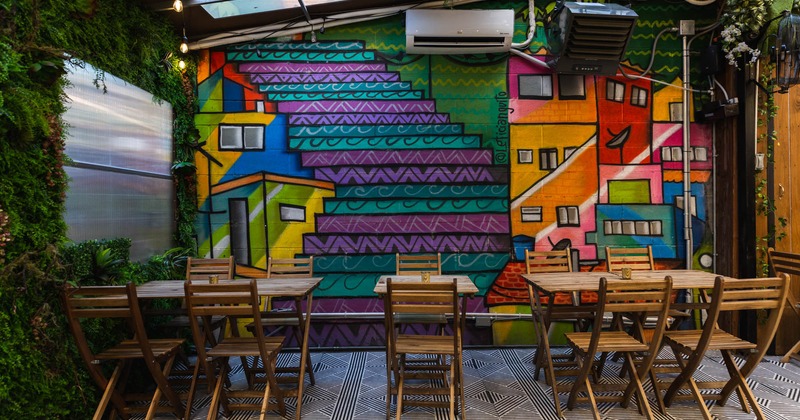 Exterior, patio, tables and seats, greenery decoration and colorful mural on a wall