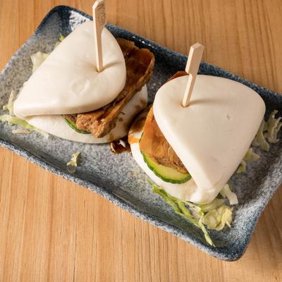 Two pork belly buns with cucumber slices and sauce inside.