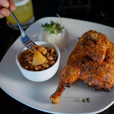 Roasted chicken, seasoned with spices, served with rice and beans