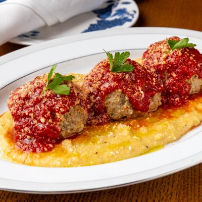 Meatballs topped with tomato sauce and grated cheese, served over polenta.
