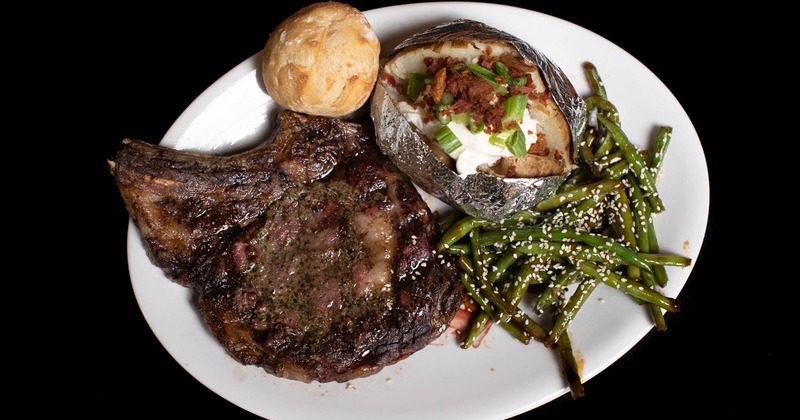 Rib eye steak with bread, baked potato and green beans on the side