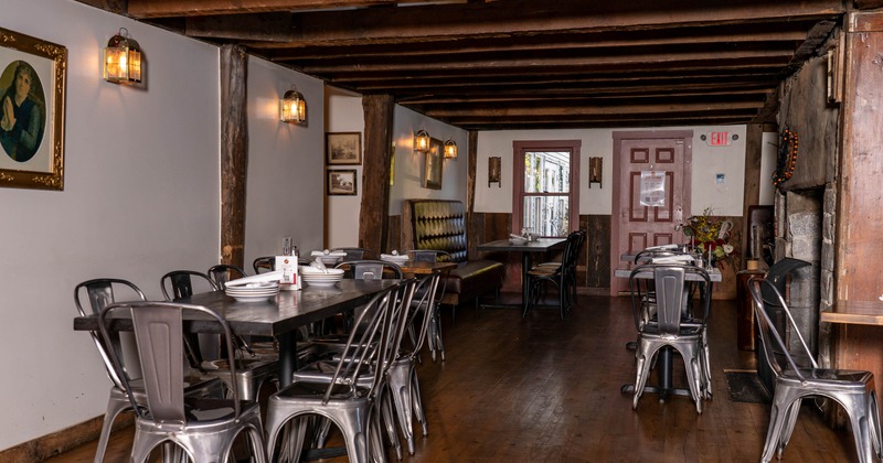 Rustic dining room with wooden floors, metal chairs, a long table with plates