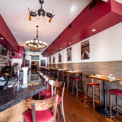 Bar area with high-top tables, red stools and wall decorations.