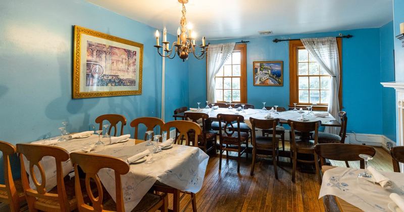 Interior, blue walls decorated with framed pictures, set tables and seats, vintage ambiance