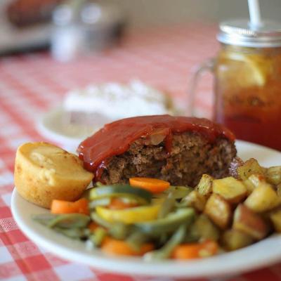 Homemade meatloaf, served with mixed vegetables, potatoes, and cornbread.