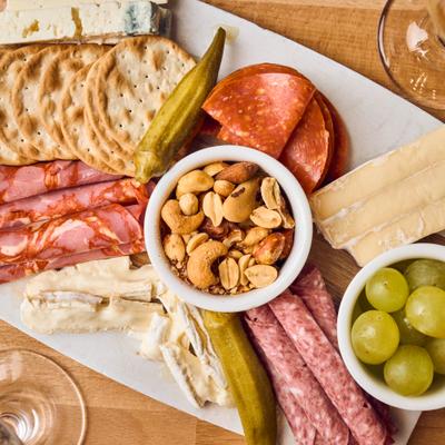Misto Board featuring artisan meats, cheeses, grapes, peanuts, crackers, and pickled okra.