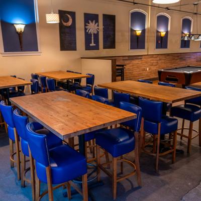 Interior with wooden tables, blue cushioned chairs, and blue wall art.