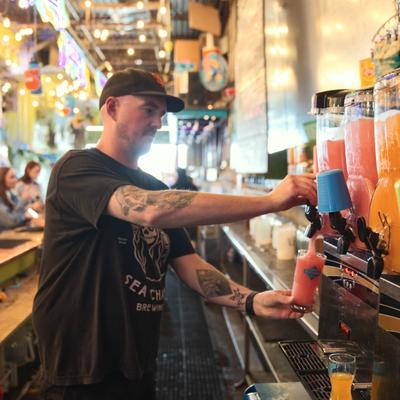 A bartender pouring a frozen cocktail form a slush machine.