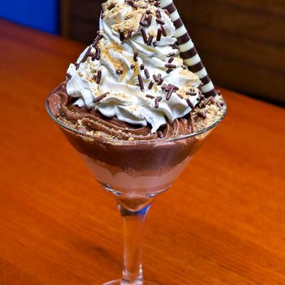 Chocolate mousse topped whipped cream, chocolate sprinkles, and a striped wafer.