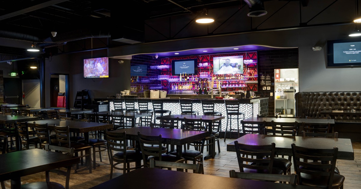 Interior, tables and chairs in the foreground and an illuminated bar counter in the background