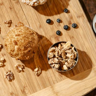 Banana nut cupcake on a wooden board surrounded by nuts and blueberries.